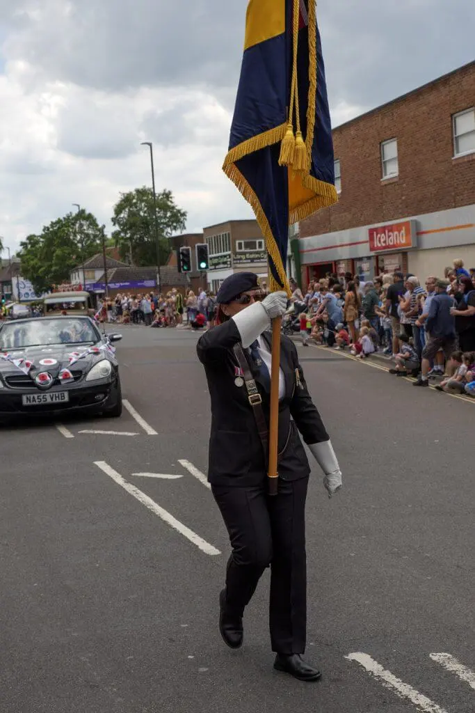 A standard bearer leading the Long Eaton Carnival parade past crowds in town