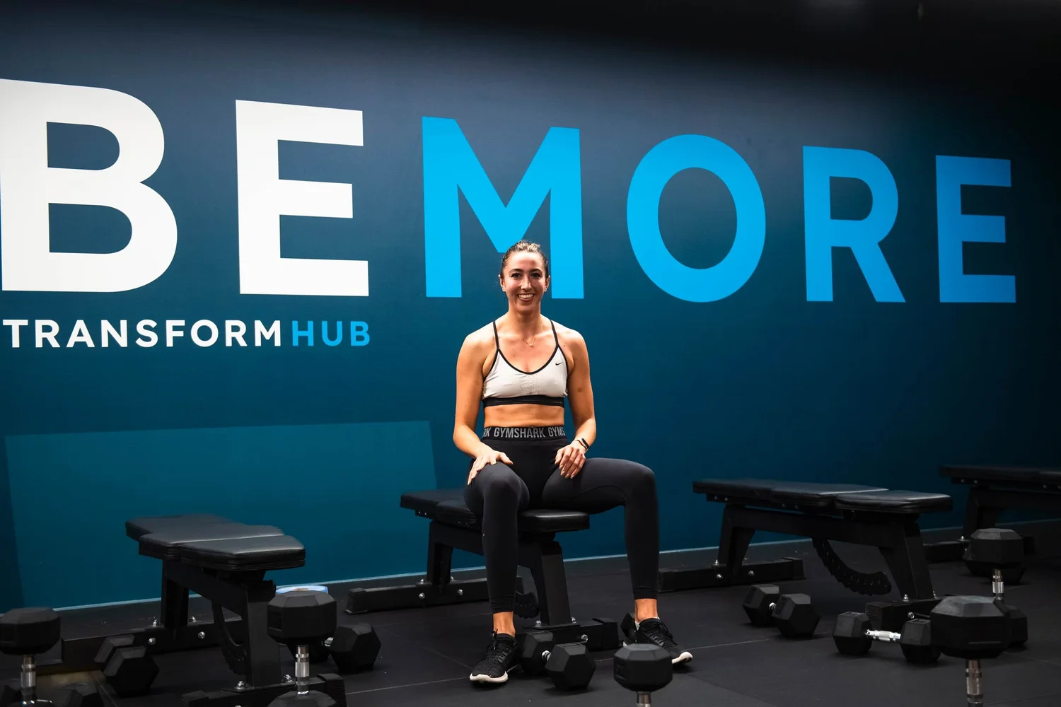 Transform Hub member in a gym beneath the Be More wall graphic
